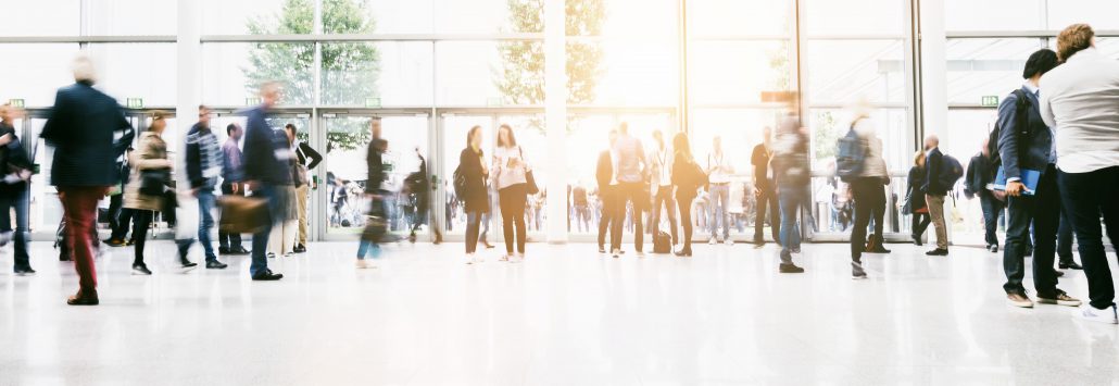 large crowd of anonymous blurred people at a trade show hall
